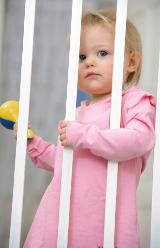 little girl behind a baby safety gate
